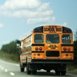 back of yellow school bus driving down the road