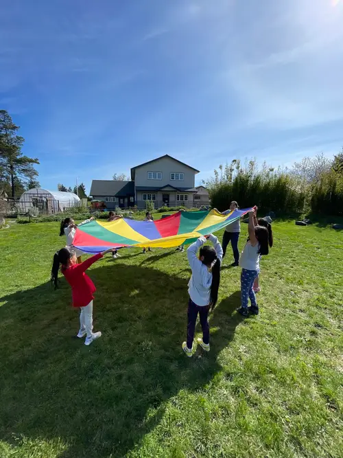 Children playing with a colorful parachute in a grassy field