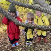 Three little children outside in their warm up suits.